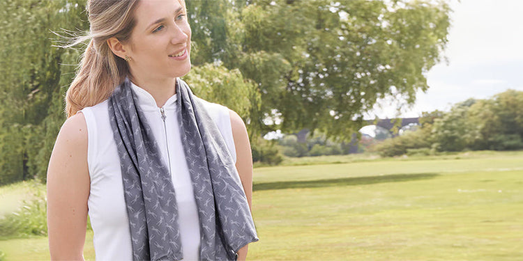Golfer wearing a grey print cool towel on a fairway