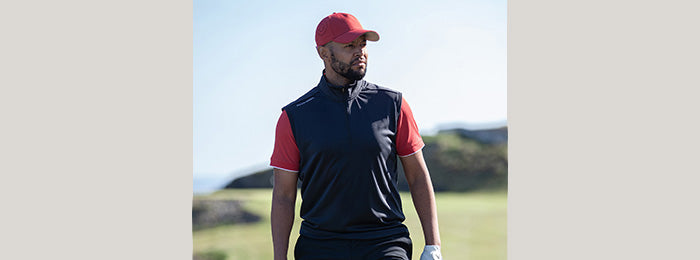 Male golfer in lightweight navy gilet and red polo shirt