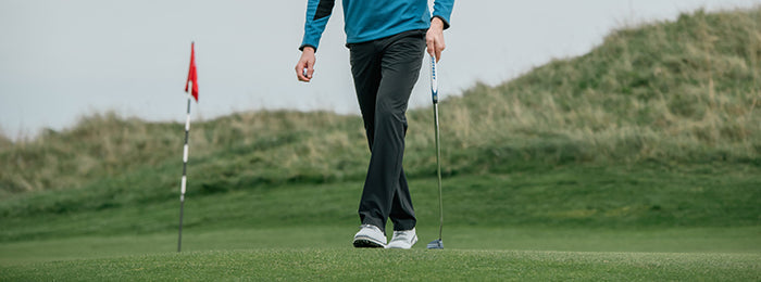 golfer in Callaway men's thermal trousers with flag in the background