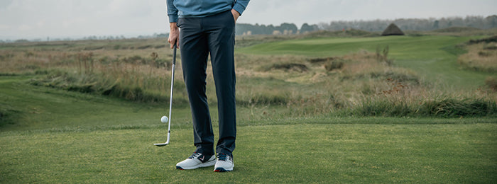 Legs of a male golfer wearing Callaway golf trousers on a green
