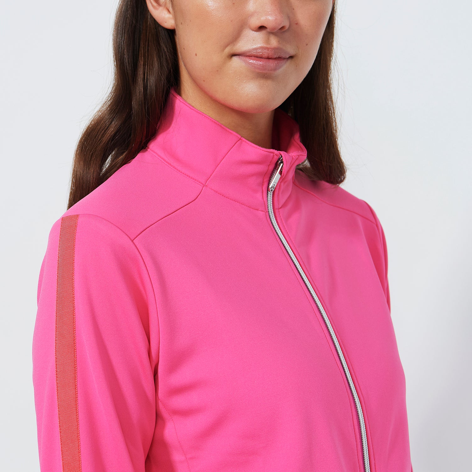 Close up cropped image of the Daily Sports ladies brushed backed warm mid layer jacket in vibrant pink with contrast orange trim on the sleeve.