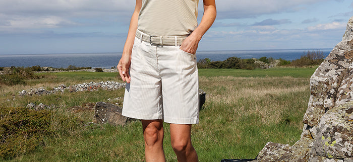 cropped image of a female golfer wearing abacus bermuda shorts in oatmeal pinstripe