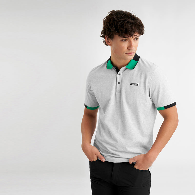 Man wearing a grey polo shirt with green and black accents from Calvin Klein golf at GolfGarb