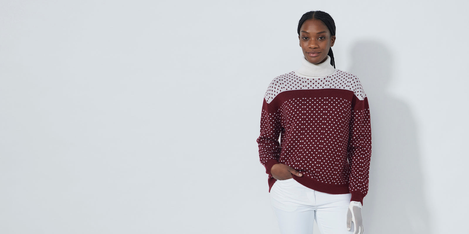 Model wearing the Daily Sports ladies knitted roll neck jumper in dot print with white and wine colours available at GolfGarb