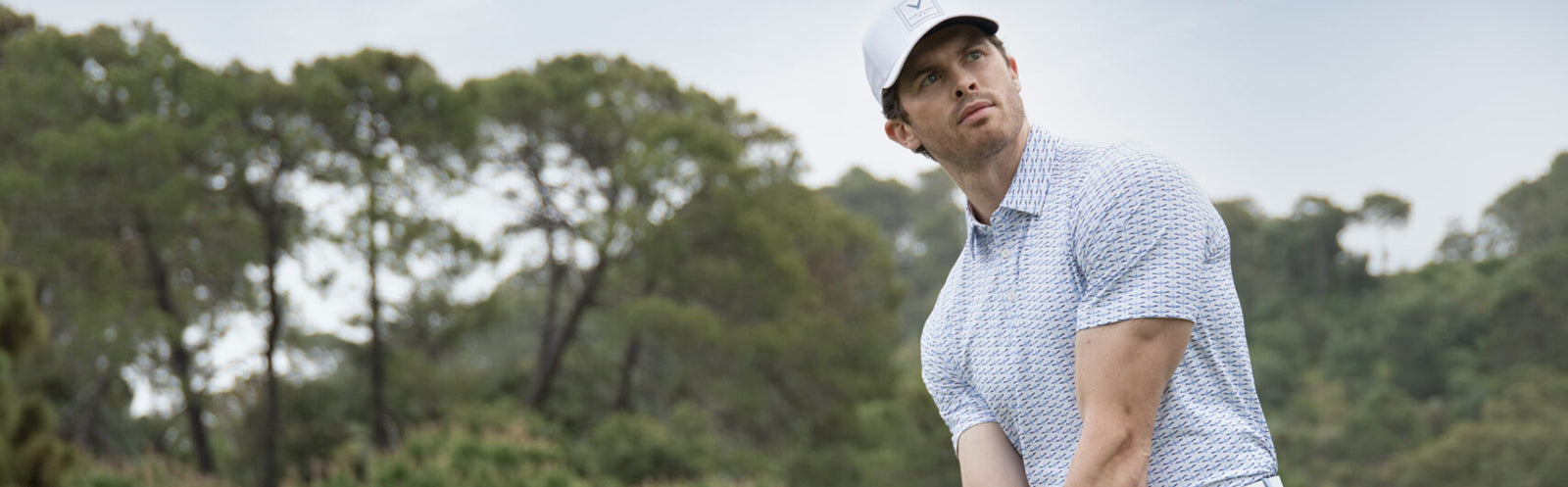 Man lining up his shot on the golf course wearing a Callaway golf polo shirt and cap.