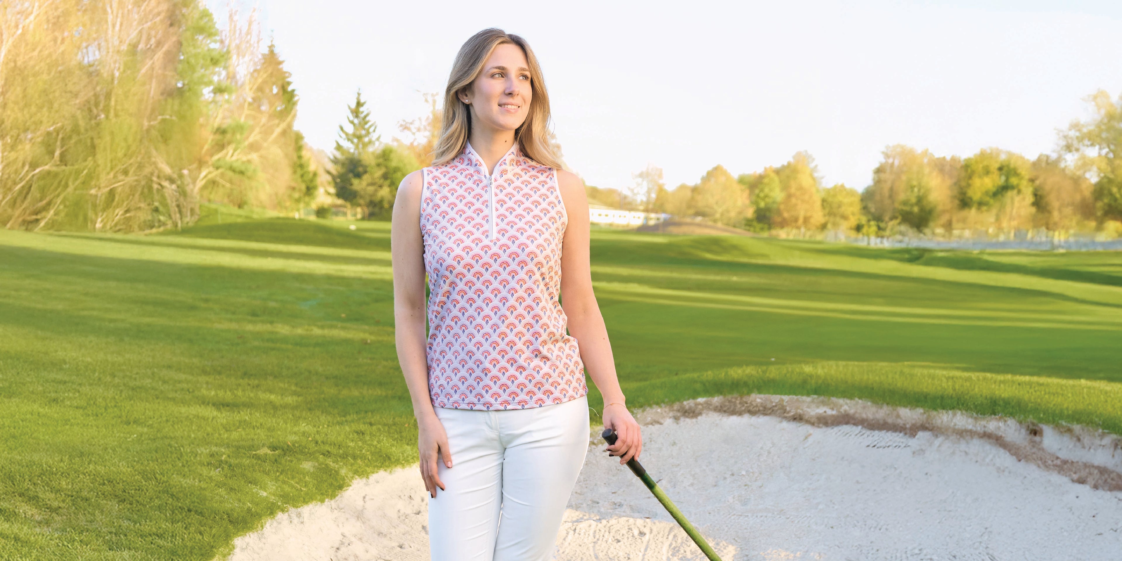 Golfer standing in a bunker holding a golf club wearing the Pure Golf sleeveless polo shirt in rainbow print