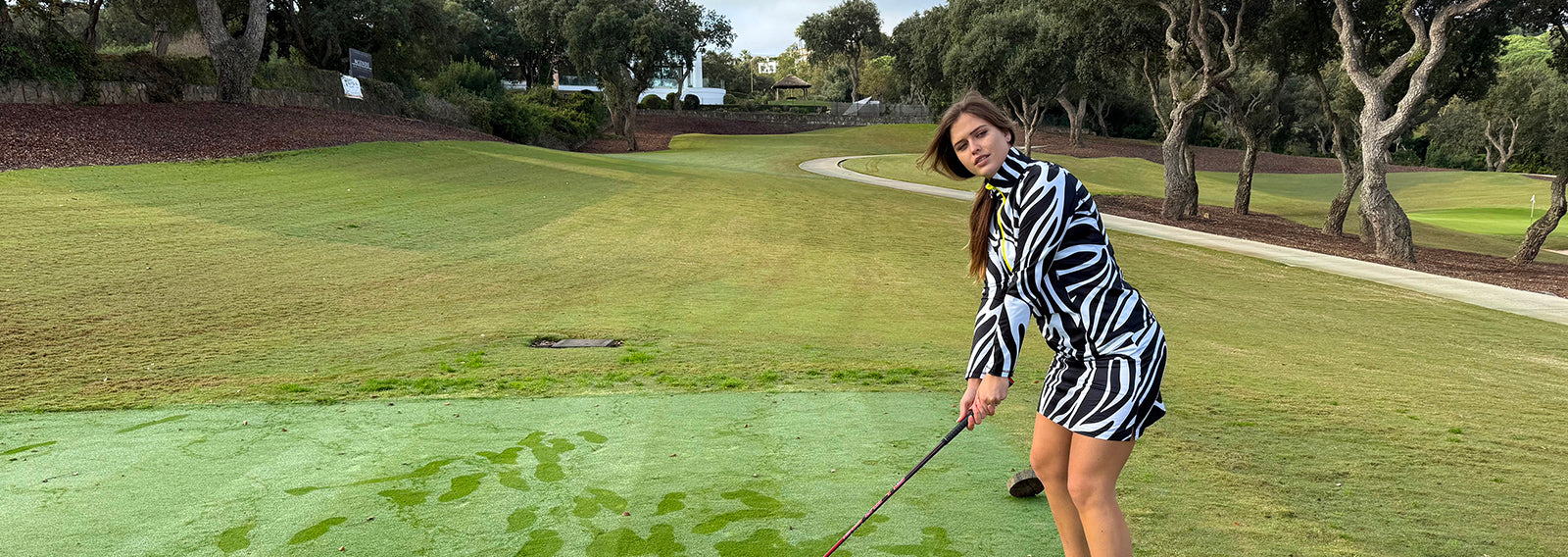 Woman in a zebra-striped outfit from Swing out Sister Golf lining up her shot