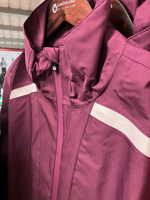 Close-up of a Sunderland of Scotland maroon ladies waterproof golf jacket with white contrast panels on a hanger